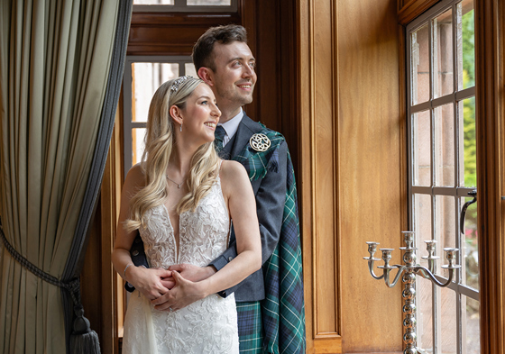 Bride and groom embrace whilst looking out window